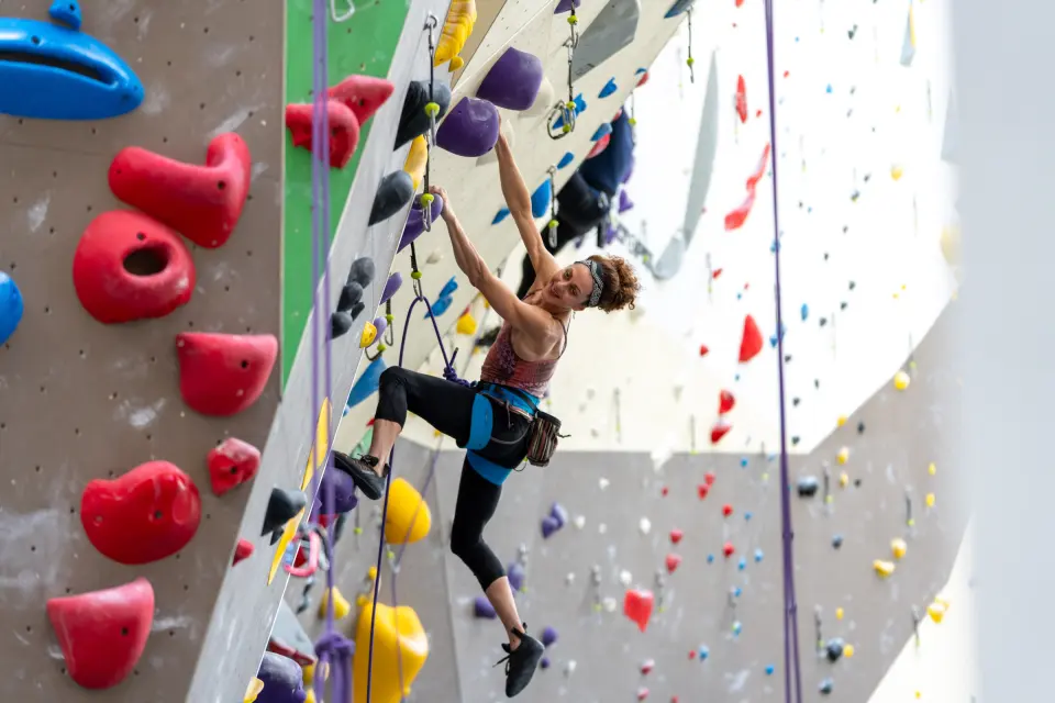 Climber on a roped route past large red holds
