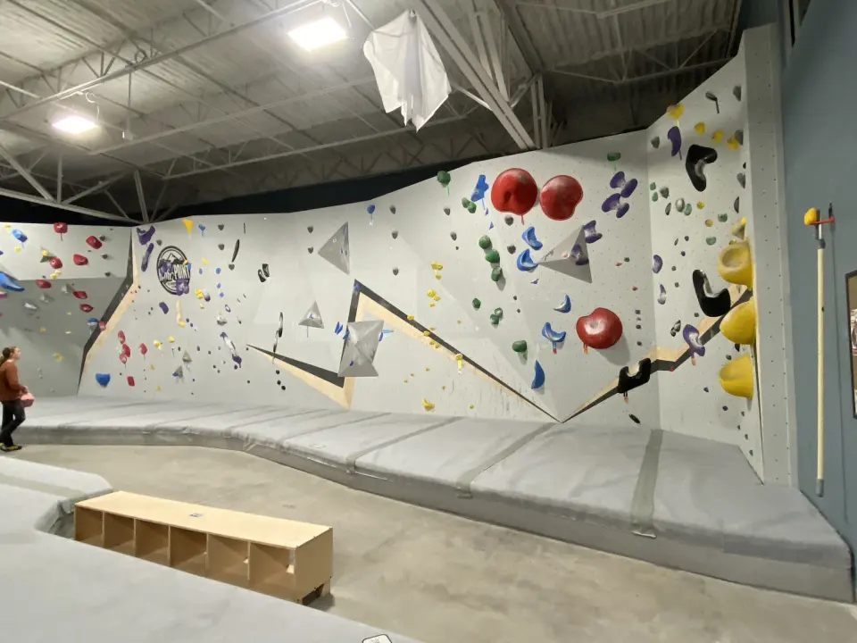 White bouldering walls above grey padded flooring