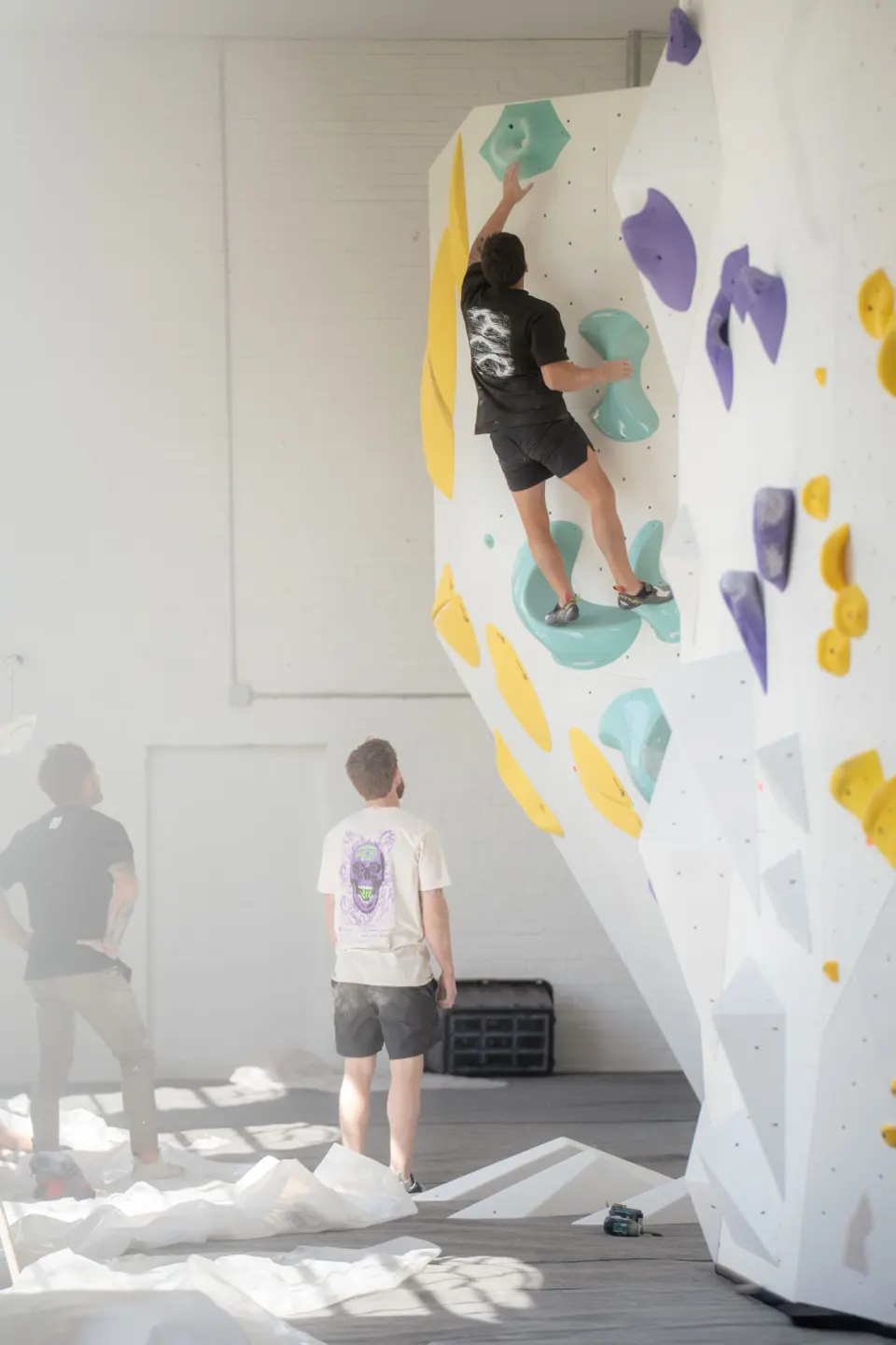 Climber on a white boulder with purple and teal holds