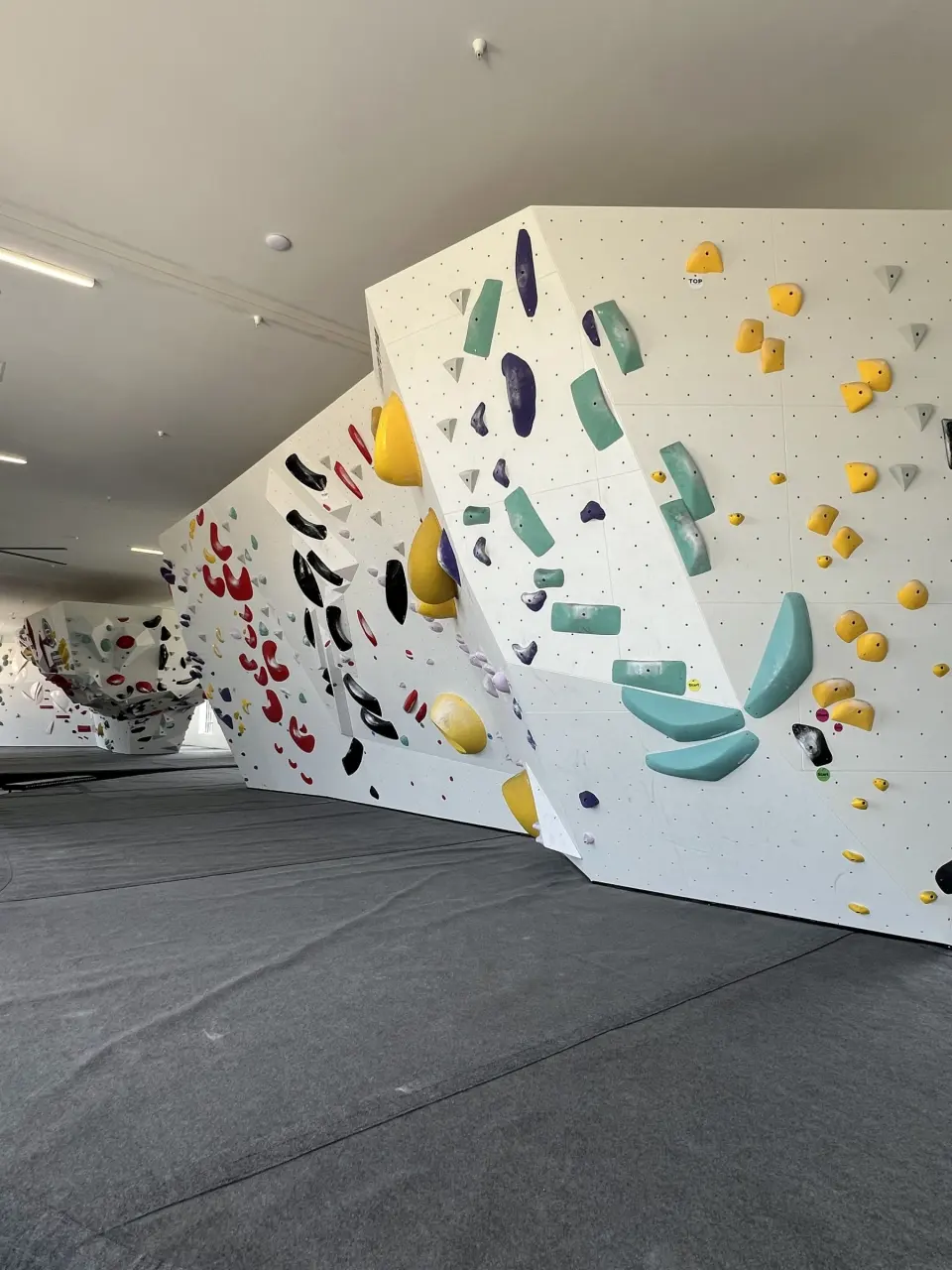 Angled white boulders with teal and yellow holds