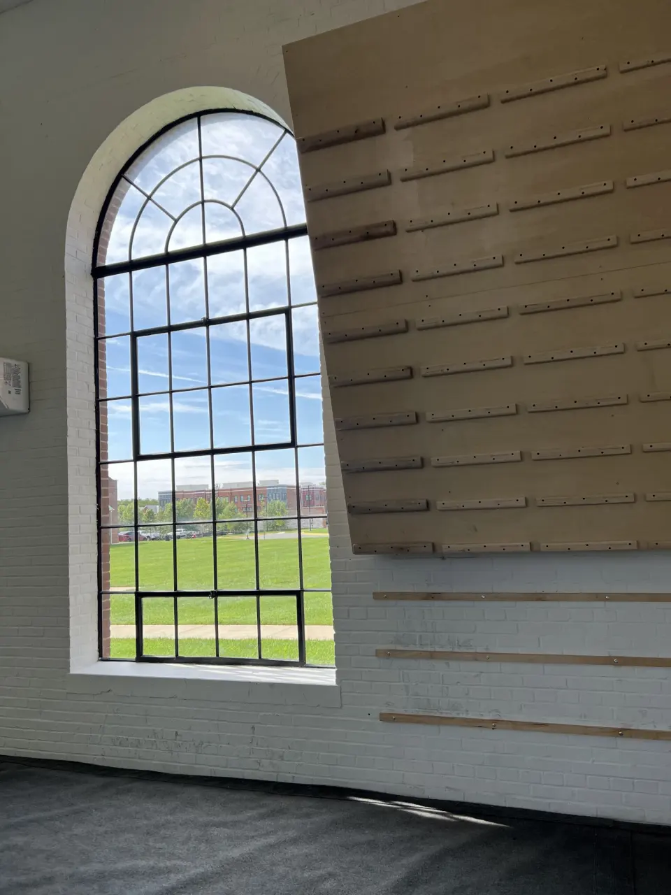 Wooden campus board next to an arched window
