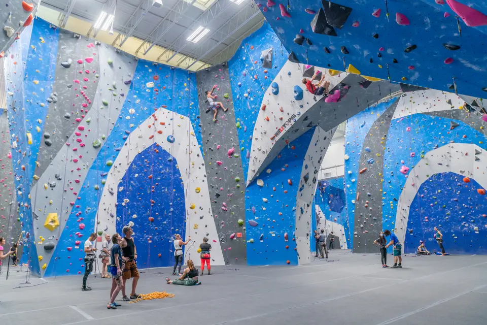 Blue and white arched roped walls with climbers gathered below