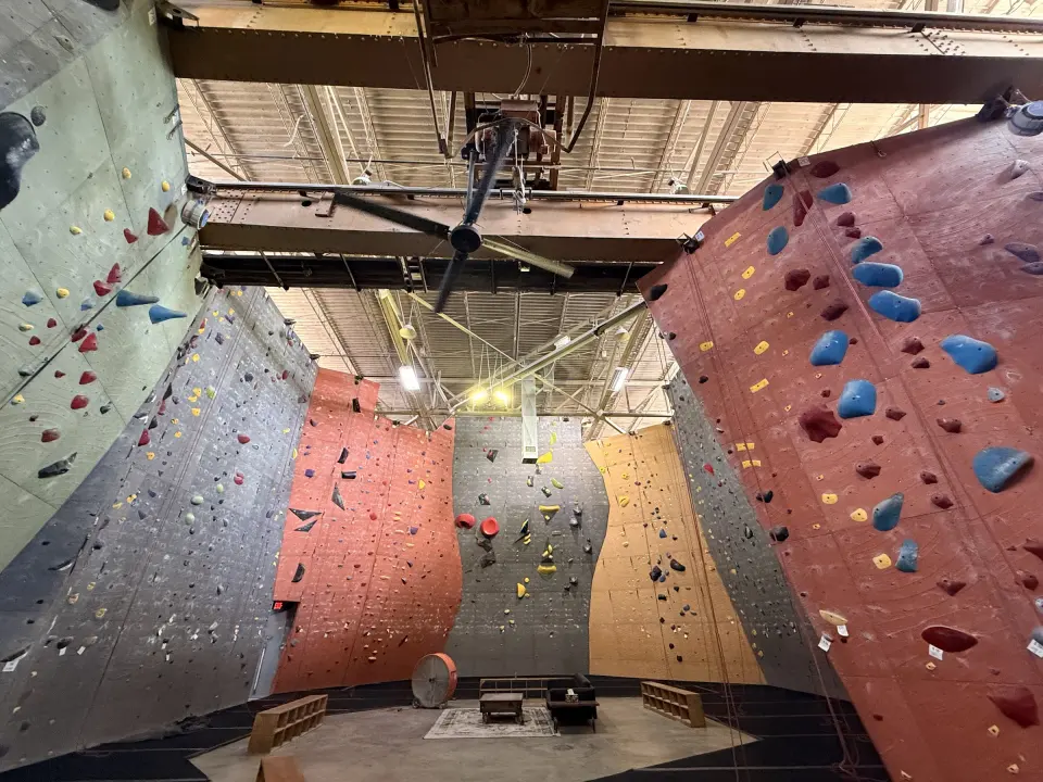 Tall top-rope walls in red, grey and yellow under the old crane beams