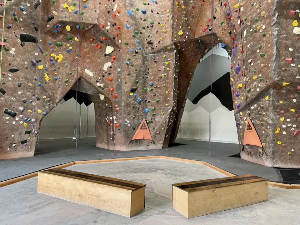 Bouldering area with arched rock-textured walls and wooden benches