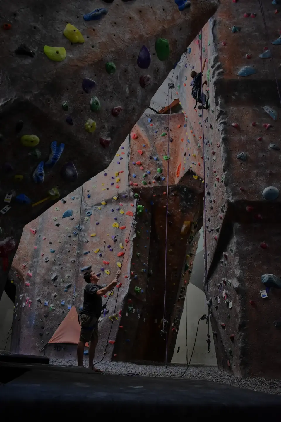 Tall roped walls with a climber belaying at the base