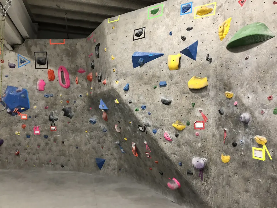 Taped boulder problems on a grey bouldering wall