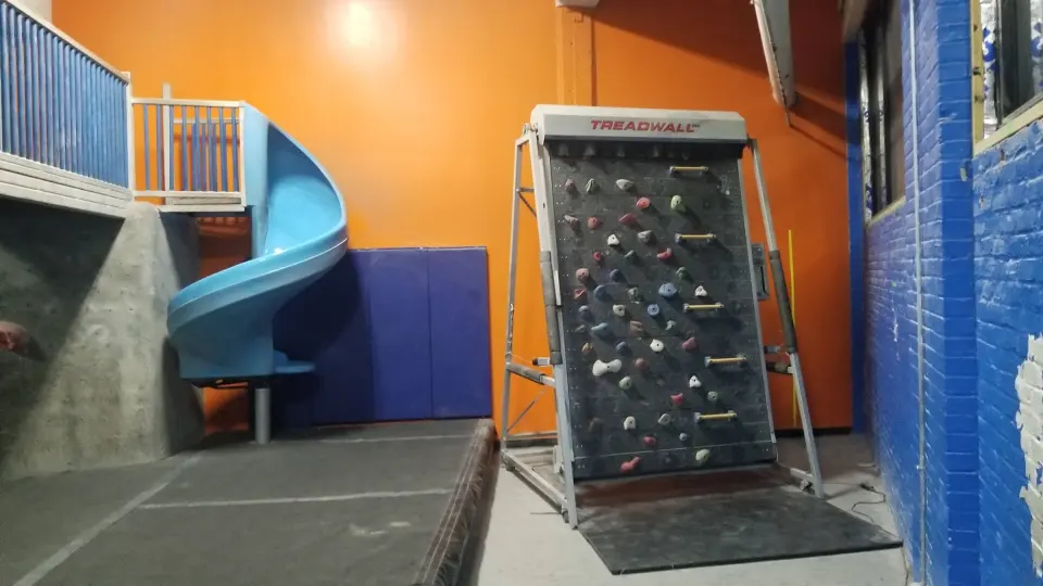 Treadwall rotating climbing wall beside a slide
