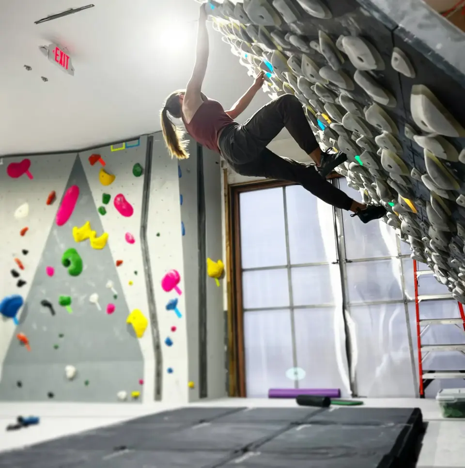 Climber on the Kilter Board beside the bouldering wall