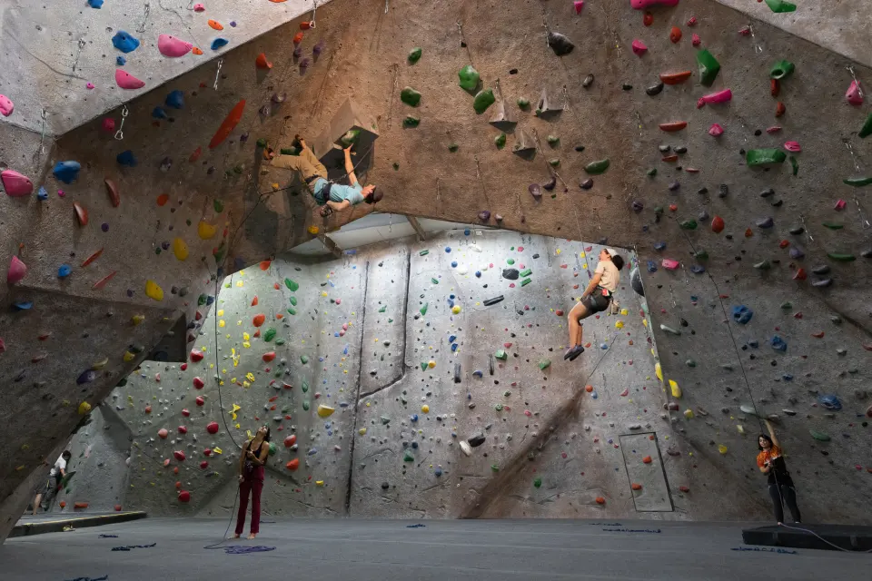 Climbers on the roped walls beneath the big arch