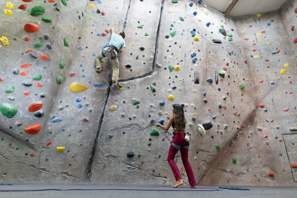 Top-rope climbers on a grey textured wall