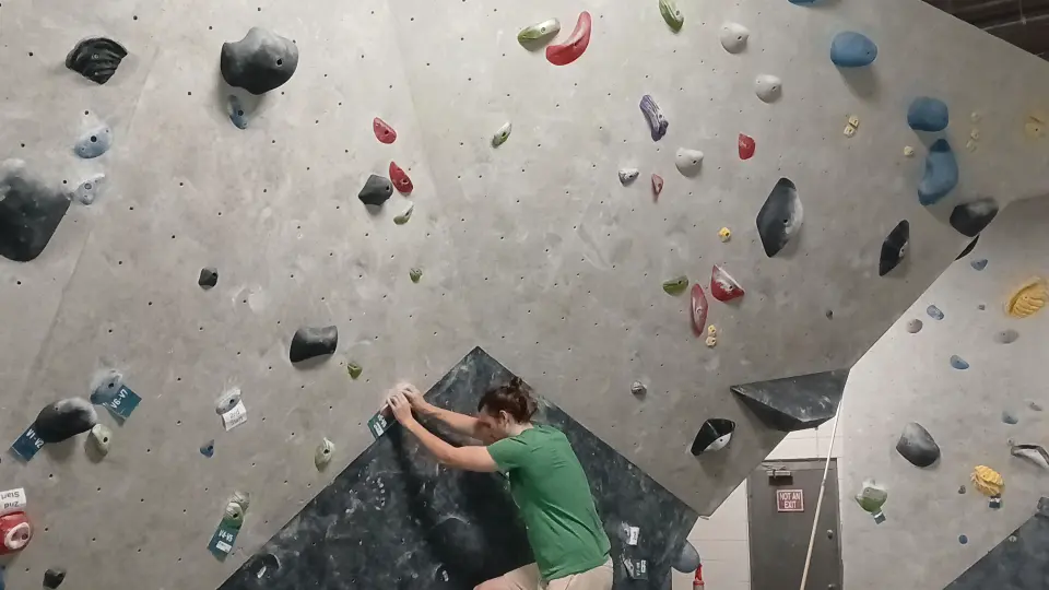 Climber starting a problem on the grey bouldering wall