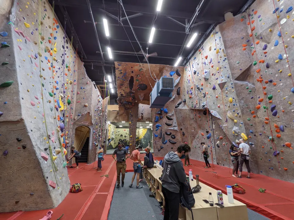 Rope-climbing hall with tall textured walls and red matting