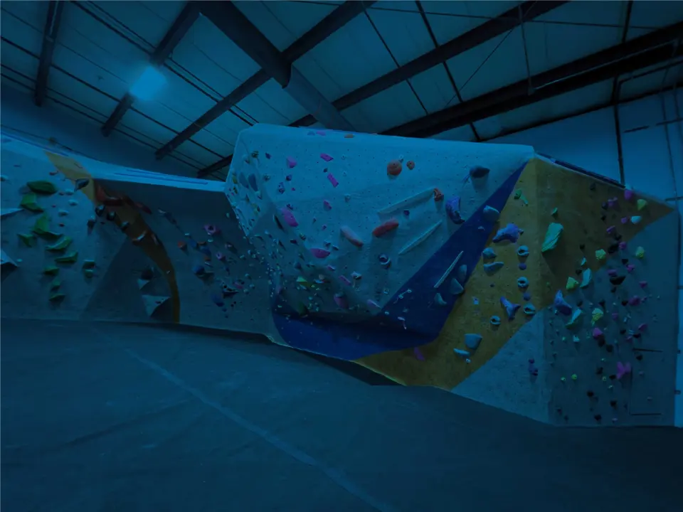 The Half Pipe bouldering wall under blue lighting