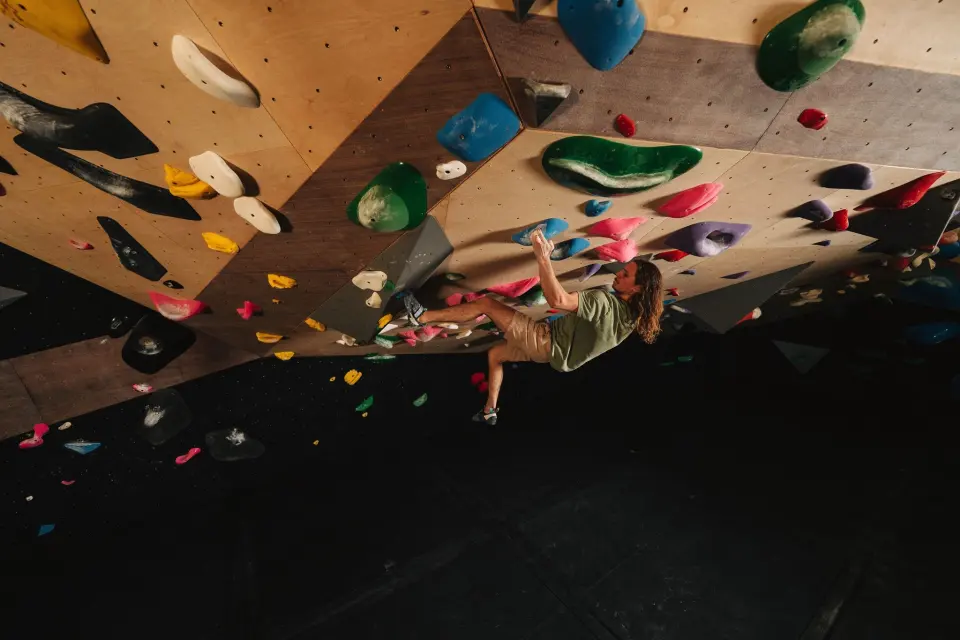 Climber reaching through an overhang on the wooden wall