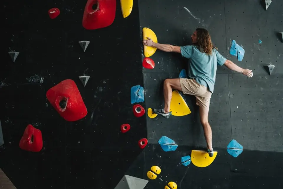 Climber on a dark grey wall with red and yellow holds