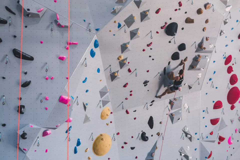 Climber on a featured wall with grey and blue panels
