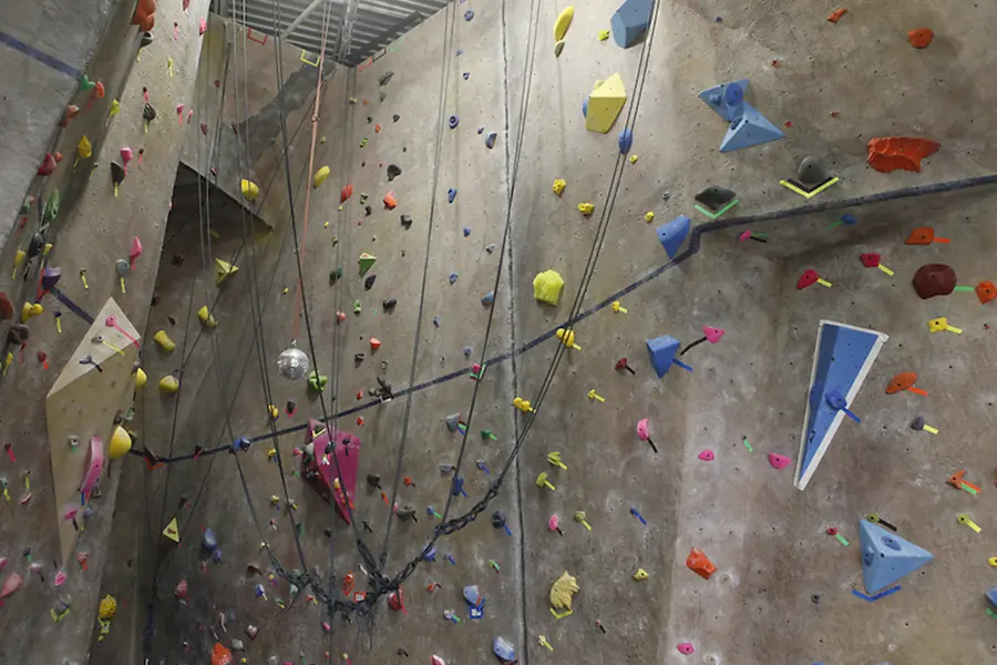 Roped climbing wall with its blue bouldering line at the UNC Campus Recreation Center