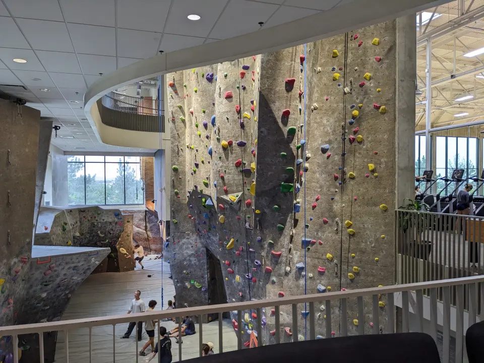 Tall roped wall and bouldering area seen from the Rec Center walkway