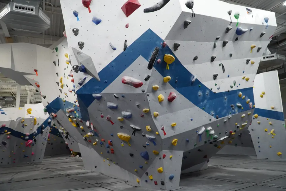 Angular white bouldering walls with a blue band over grey matting
