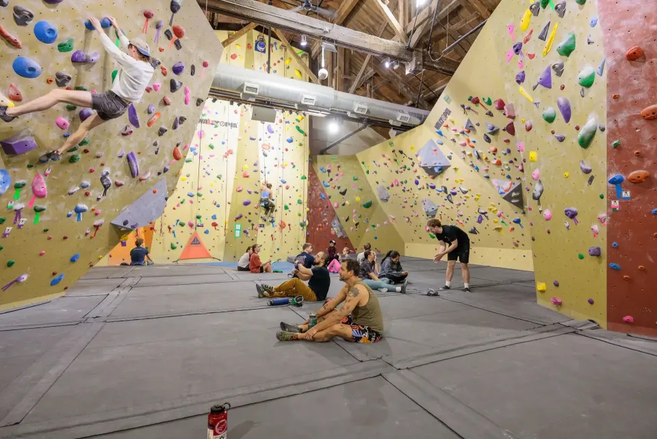 Bouldering hall with a climber on an overhang under the timber roof