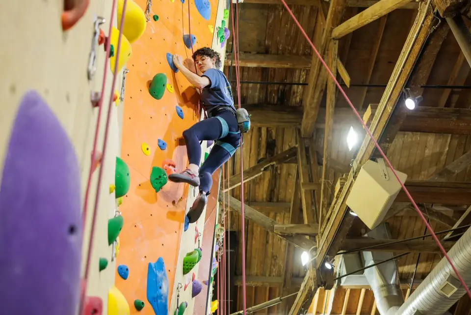 Roped climber high on an orange and yellow wall