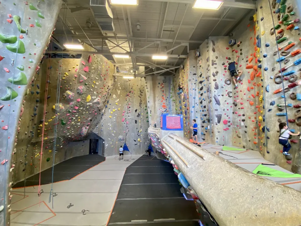 Long hall of tall climbing walls with bouldering below
