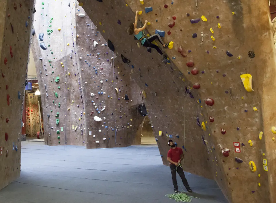 Tall textured lead walls with a climber high up