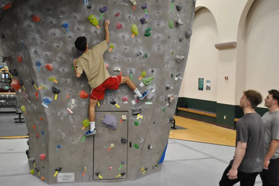 Climber bouldering low on the wall as others watch