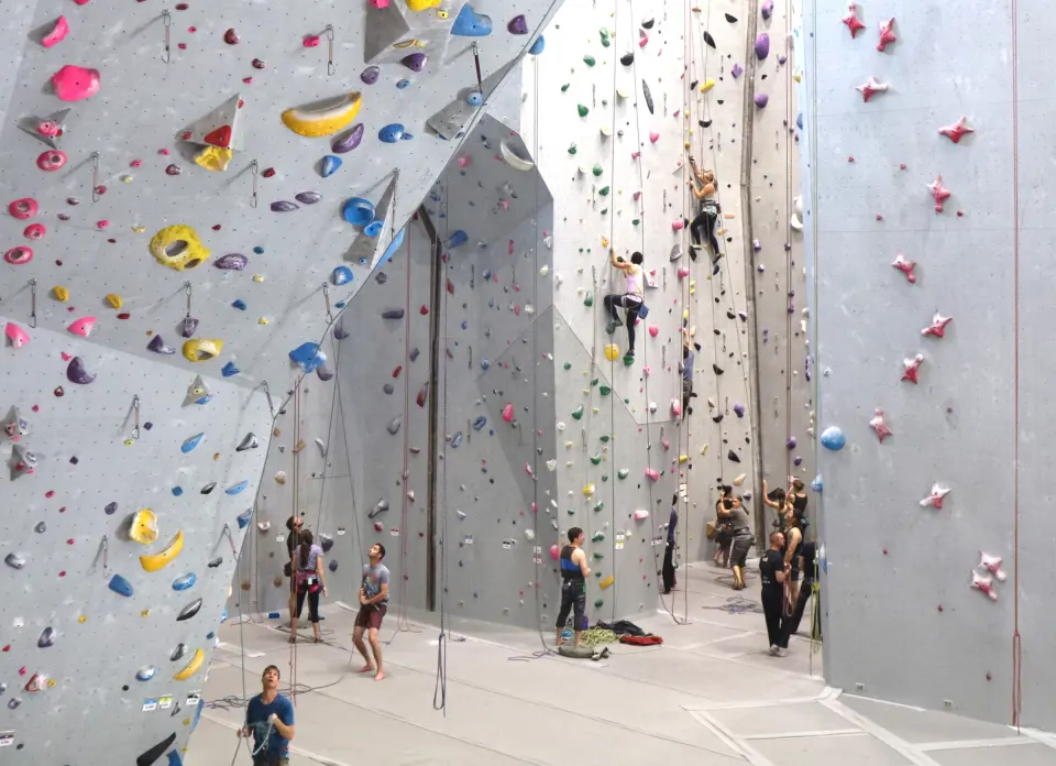 Climbers on the tall grey roped walls