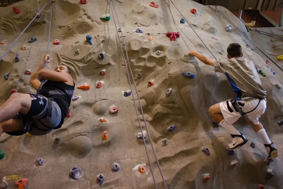 Two climbers on the textured climbing wall in the SunUte gymnasium