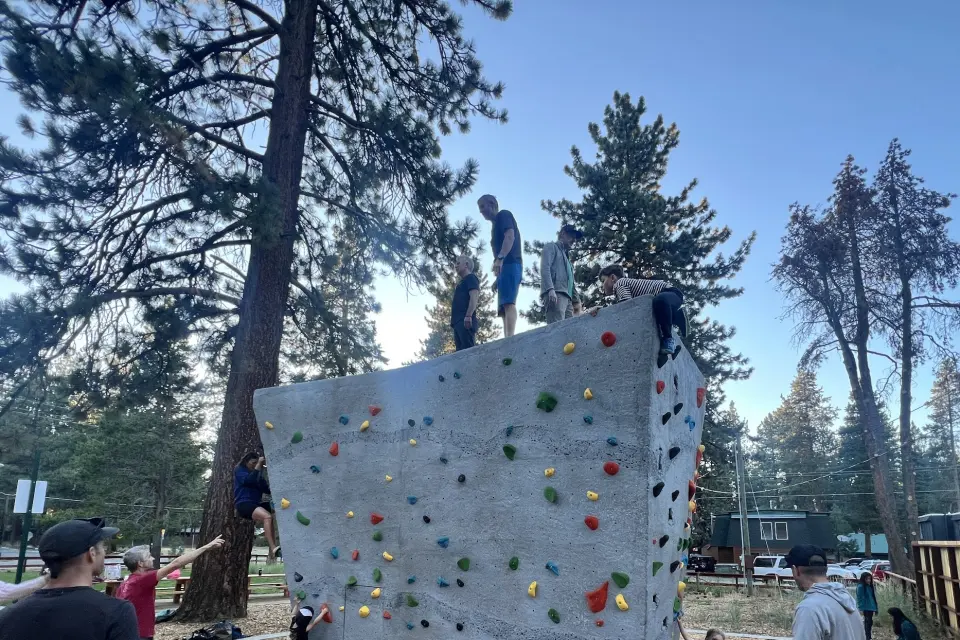 Climbers on top of the grey bouldering block in Ski Run Community Park