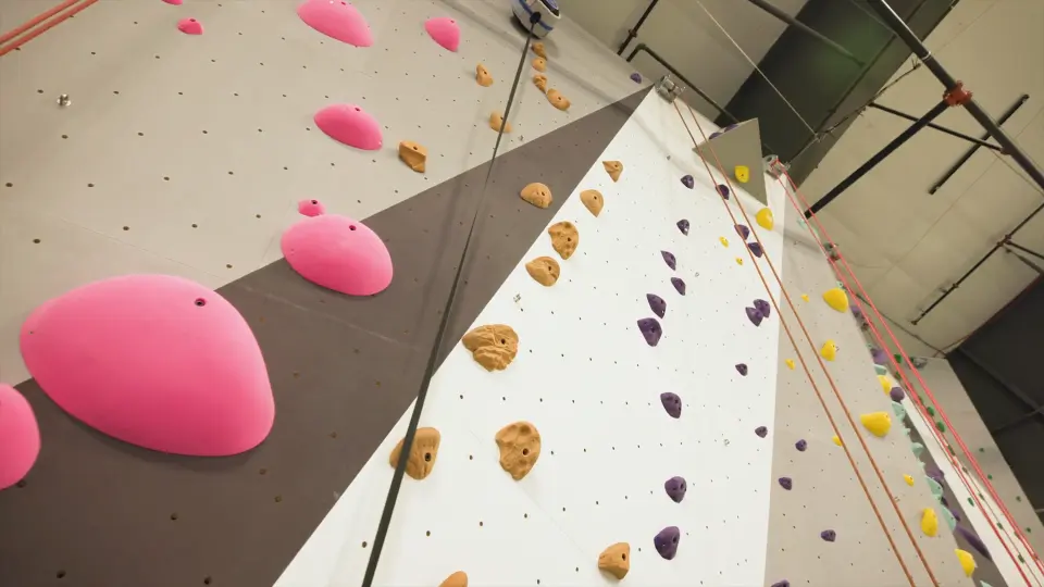 Pink volumes and coloured holds on the roped wall