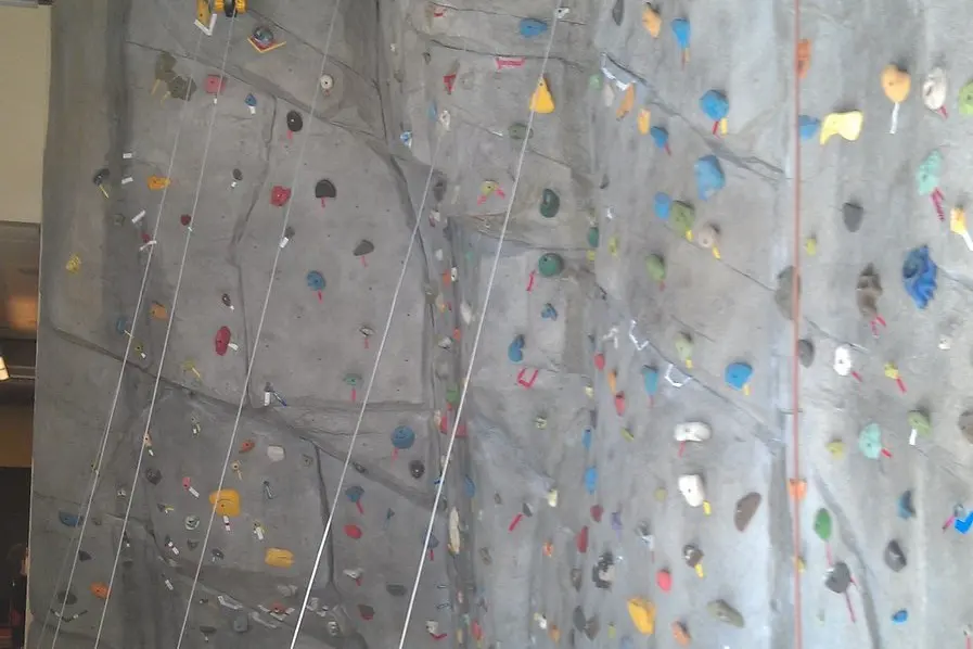 Top ropes hanging down the sculpted grey climbing wall