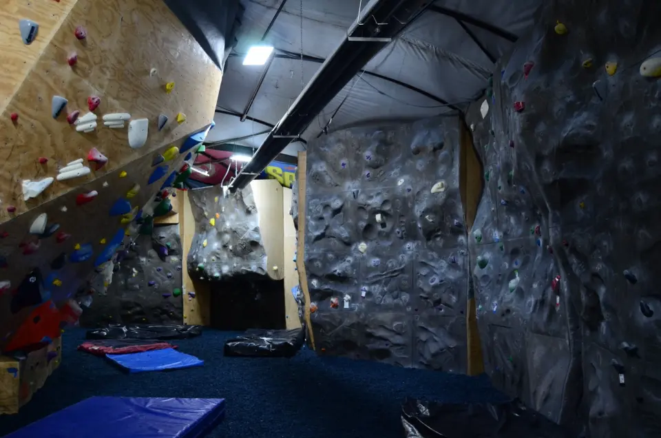 Textured grey rock-style walls with blue mats on a rubber-chip floor