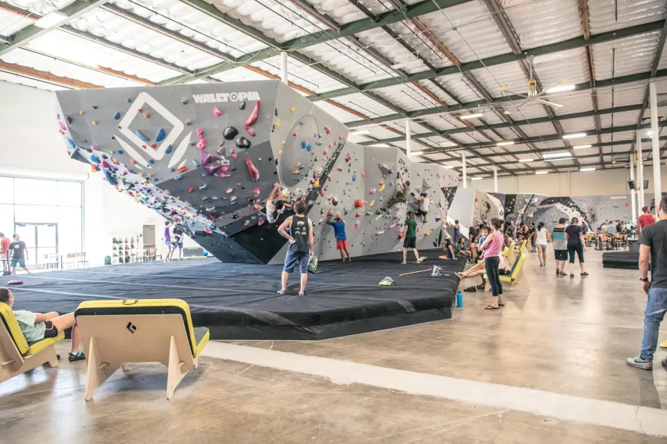 Bouldering hall with an angular overhanging feature wall, padded floor and lounge chairs