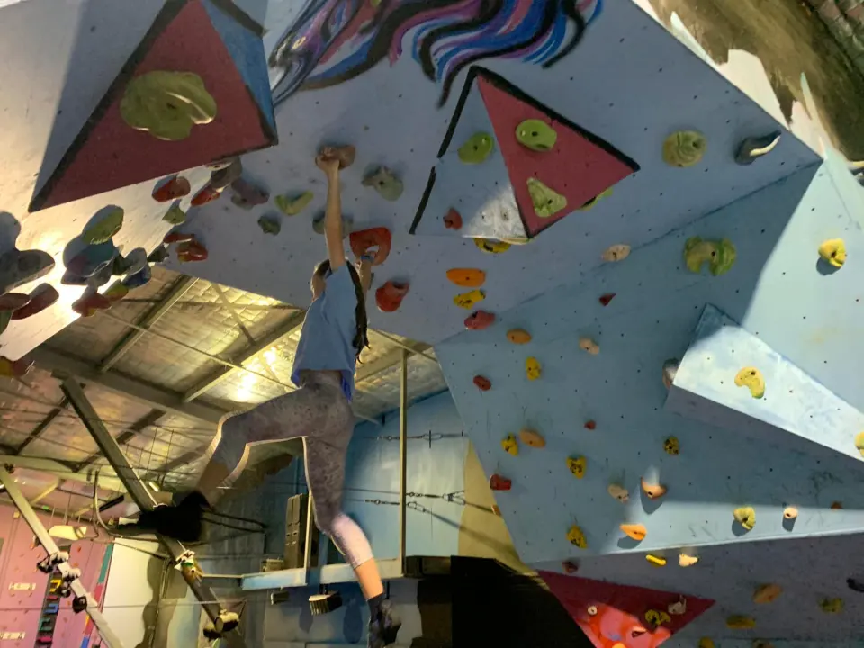 Climber on the overhanging wall below a painted mural