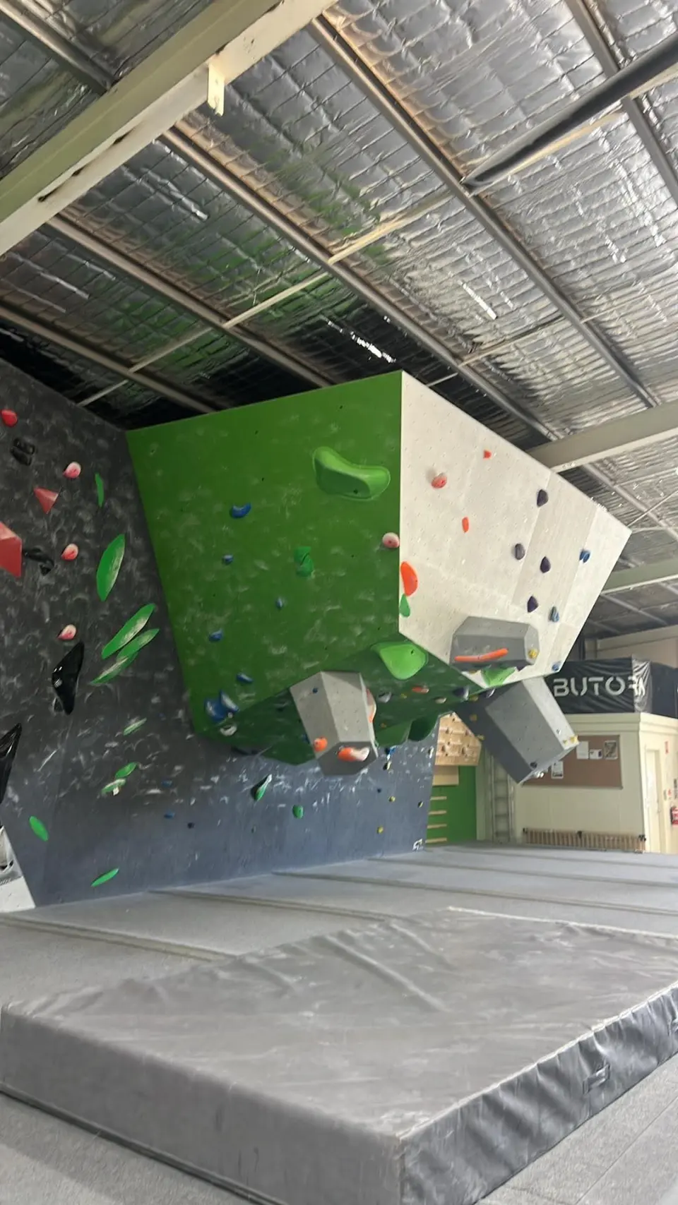 Overhanging green and white boulder above thick matting