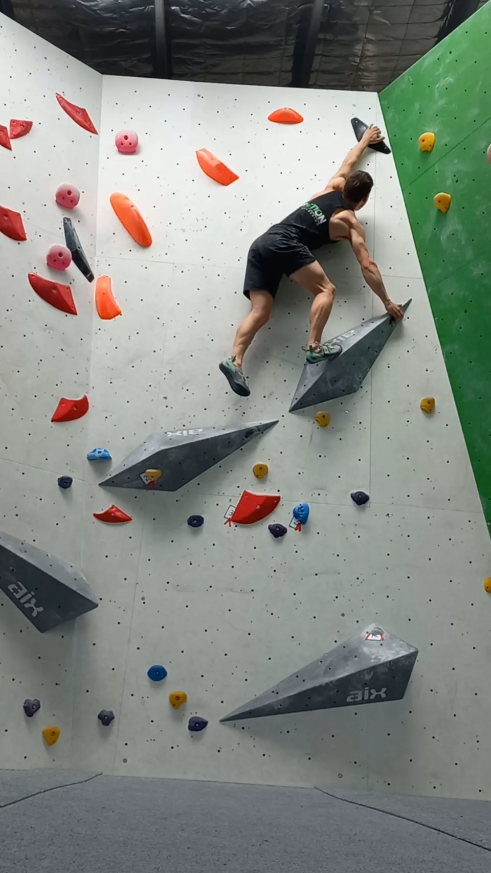 A climber bridging between volumes in a white corner