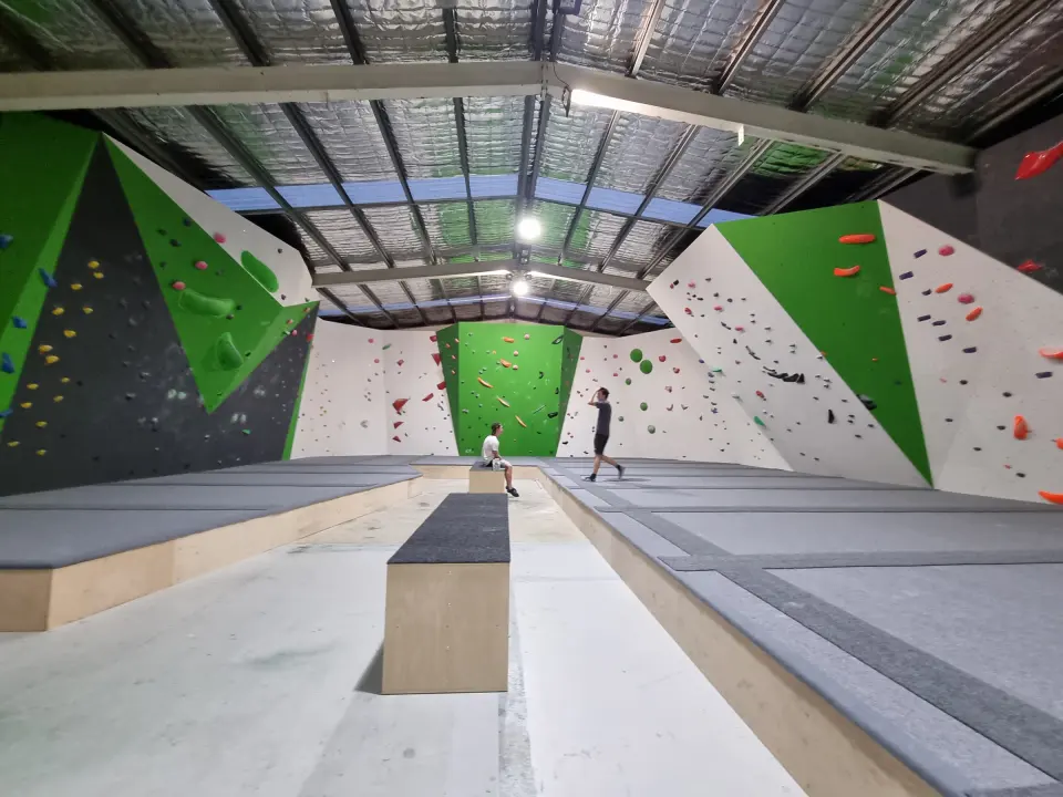The bouldering hall, with green and white walls either side of the matting