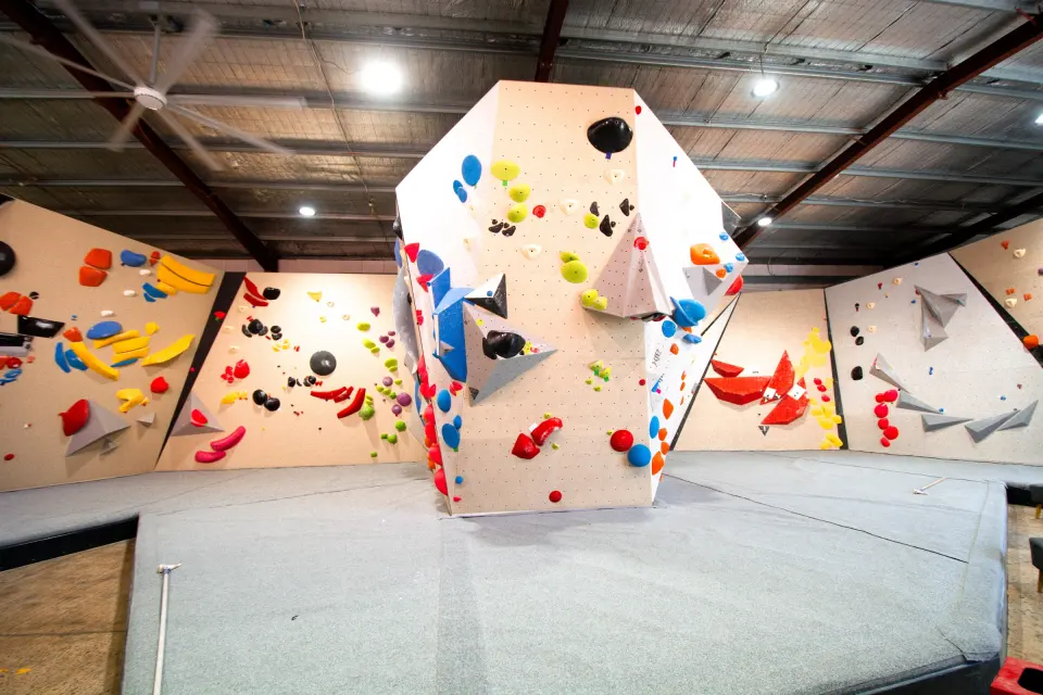 Tower boulder surrounded by bouldering walls under the warehouse roof