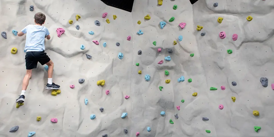Young climber on the textured indoor bouldering wall