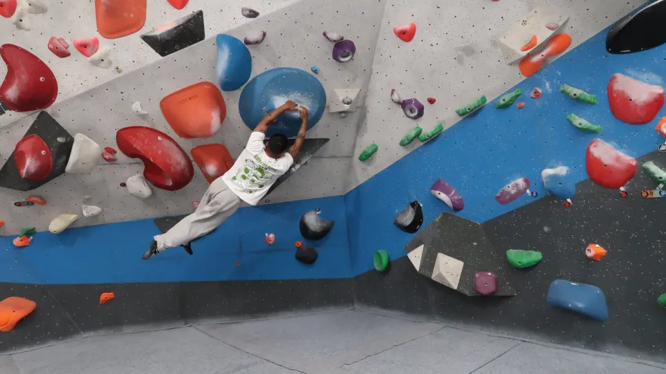 Climber traversing a white and blue wall on red and blue holds