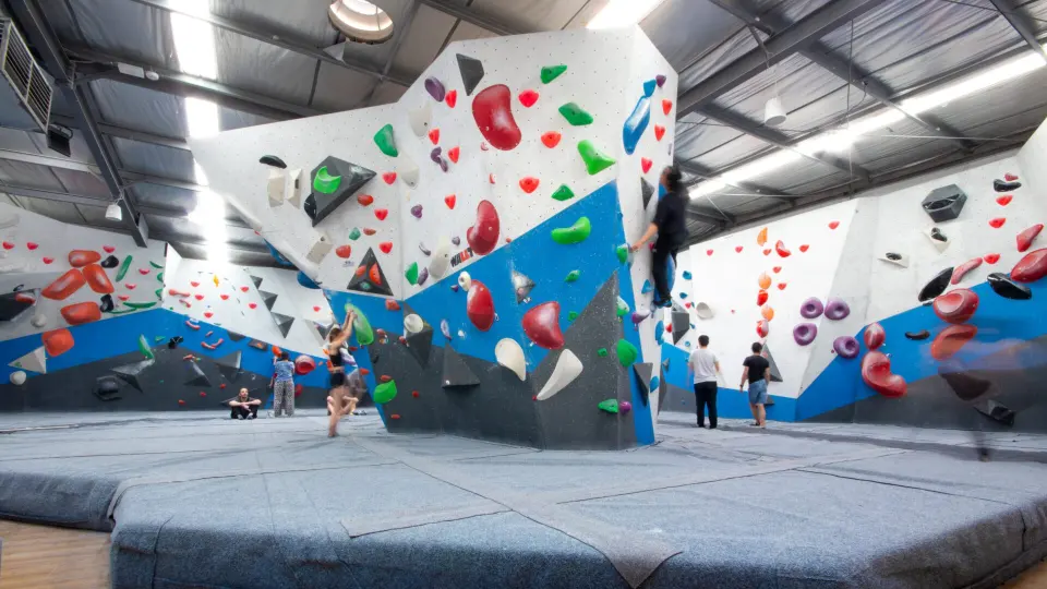 Main bouldering area with a tall freestanding block and white and blue walls