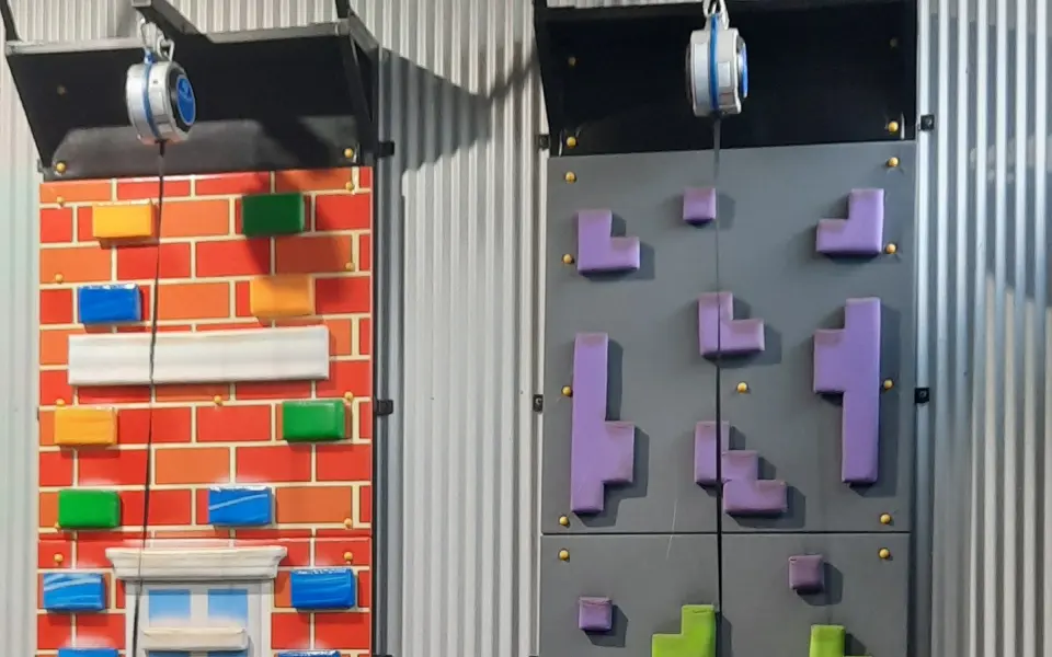 Two auto-belay climbing walls, one painted as brickwork and one with block-shaped holds