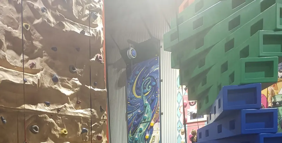 The textured rock-style climbing wall next to a painted wall and the stacked-block tower