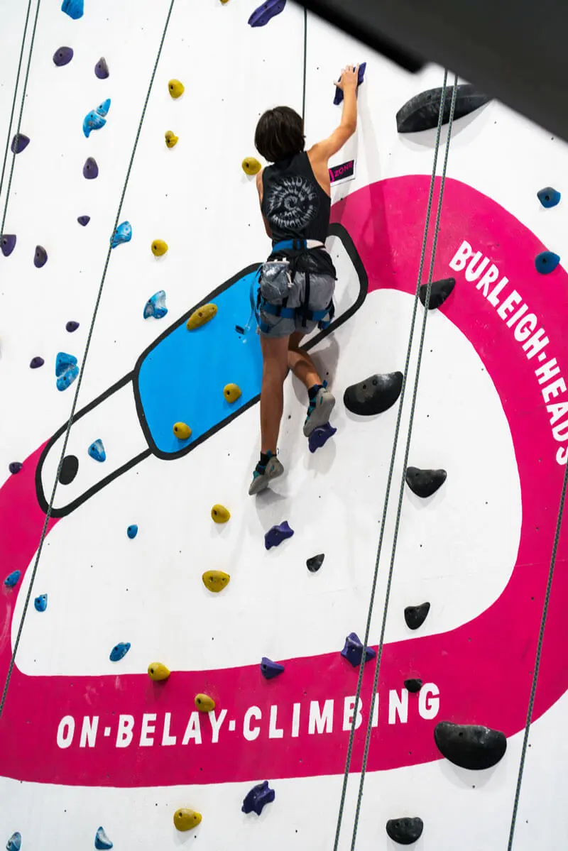 Climber high on the wall painted with the On Belay logo