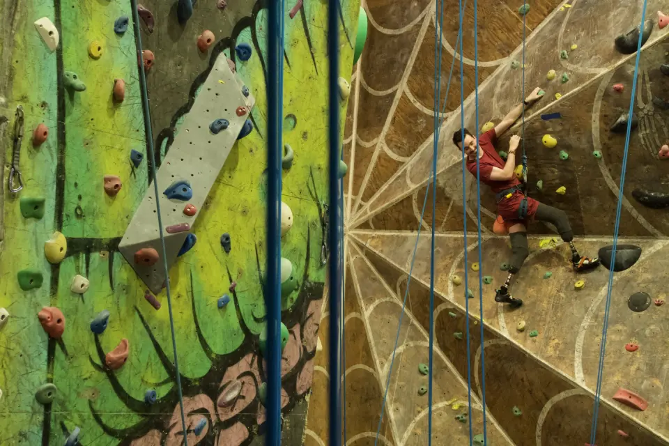 Para climber on the spider-web wall beside the green mural