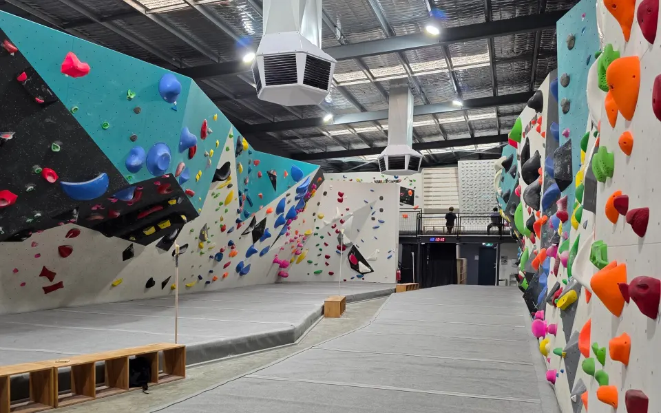 Bouldering hall with teal and white walls above grey matting