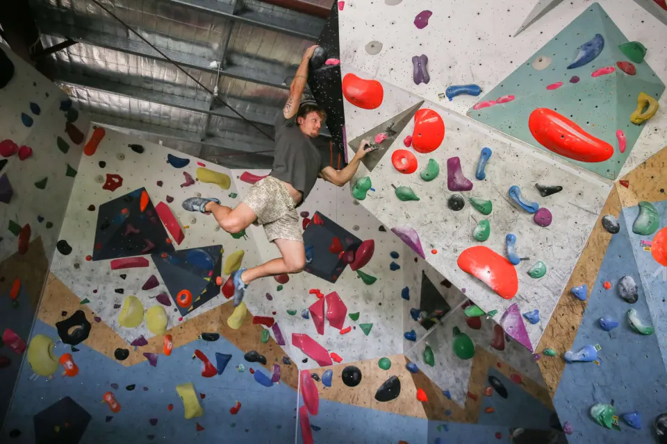 Climber moving across the steep, hold-covered bouldering wall