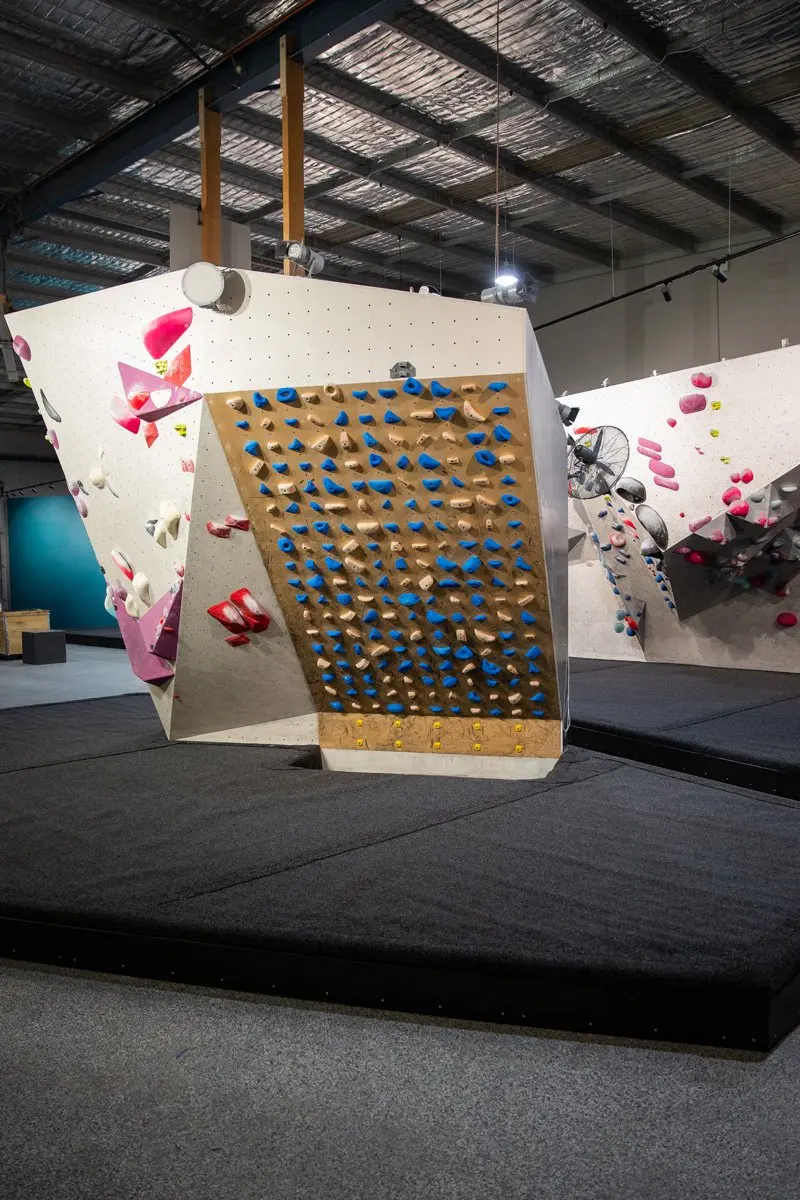 Free-standing training board beside white bouldering walls